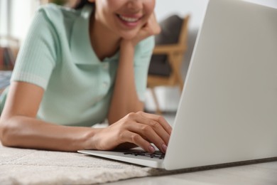 Photo of Young woman working with laptop on floor at home, closeup