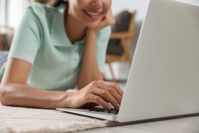 Young woman working with laptop on floor at home, closeup