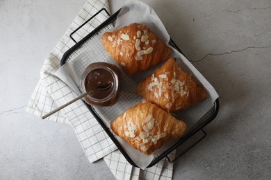 Delicious croissants with almond flakes and chocolate paste on light grey table, top view