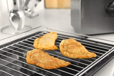 Photo of Delicious fried chebureki with tasty filling on metal grid