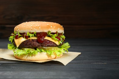 Burger with delicious patty on black wooden table, space for text