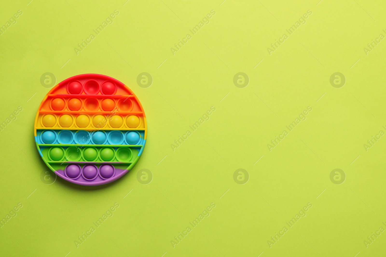 Photo of Rainbow pop it fidget toy on light green background, top view. Space for text