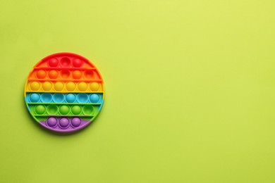 Photo of Rainbow pop it fidget toy on light green background, top view. Space for text