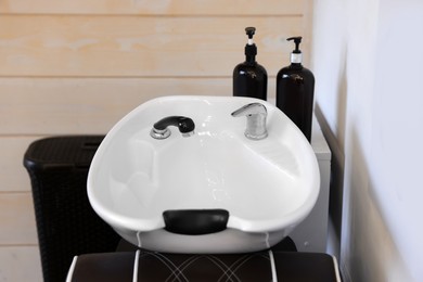 Photo of Modern wash unit with professional care products in barbershop