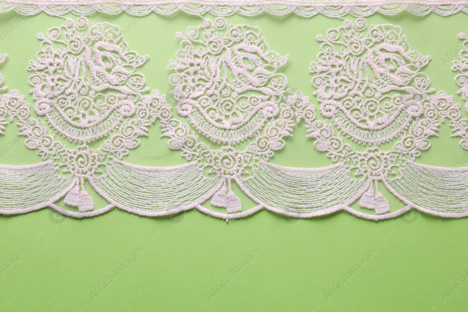 Photo of White lace on green background, top view. Space for text