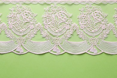 Photo of White lace on green background, top view. Space for text