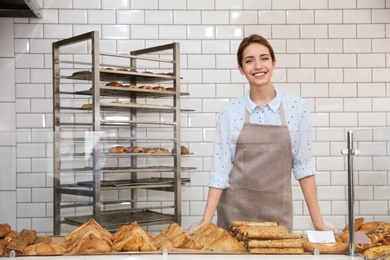 Photo of Beautiful woman near showcase with pastries in bakery shop