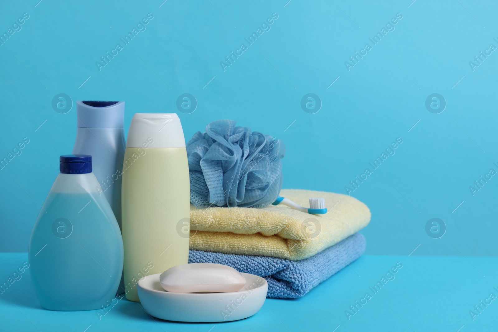 Photo of Baby cosmetic products, accessories and towels on light blue background. Space for text