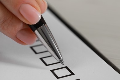Woman filling check boxes with pen, closeup. Space for text