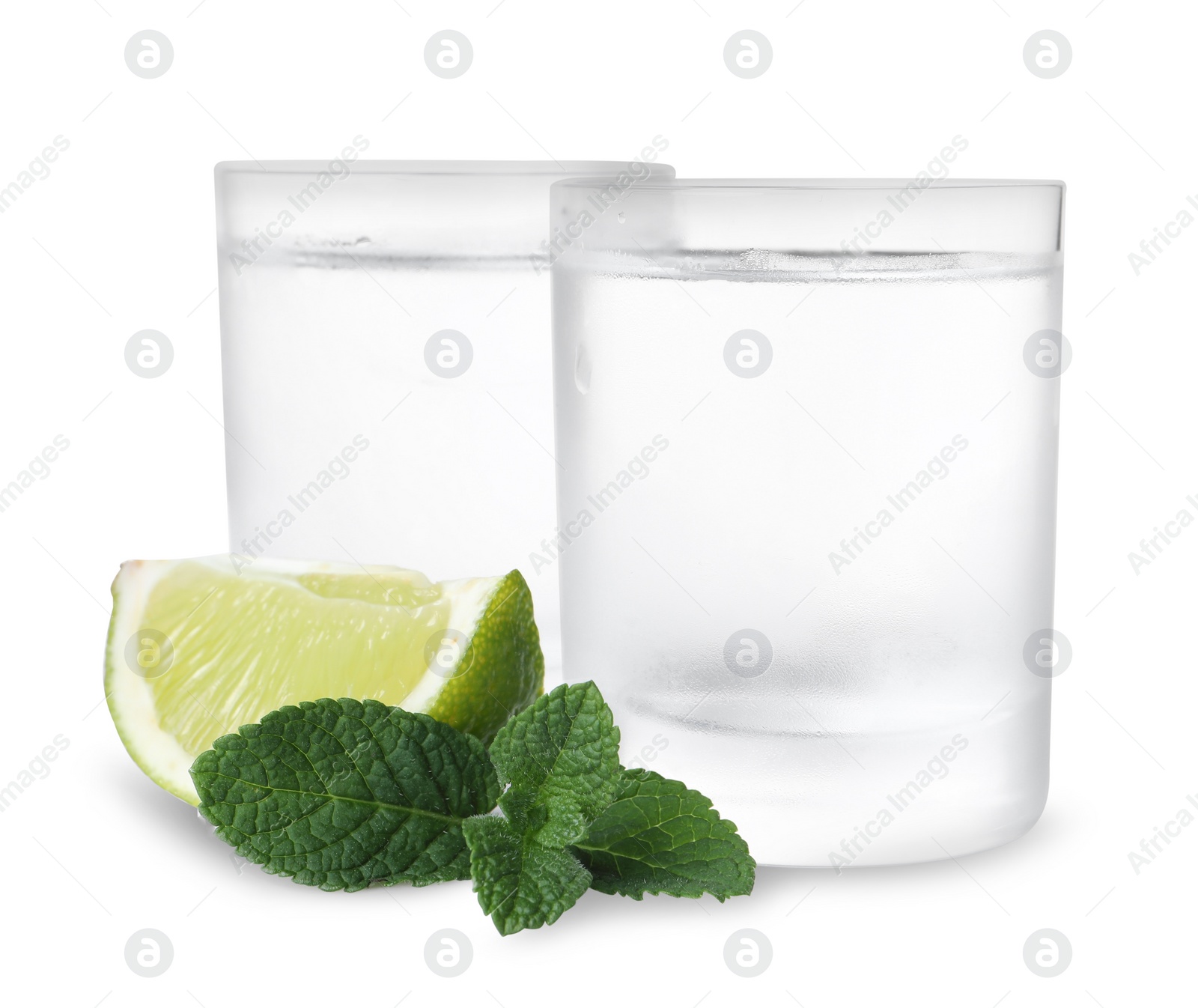 Photo of Glasses of vodka, mint and lime isolated on white