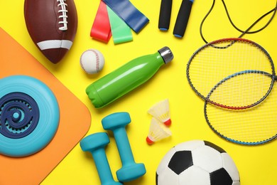 Flat lay composition with sports equipment on yellow background