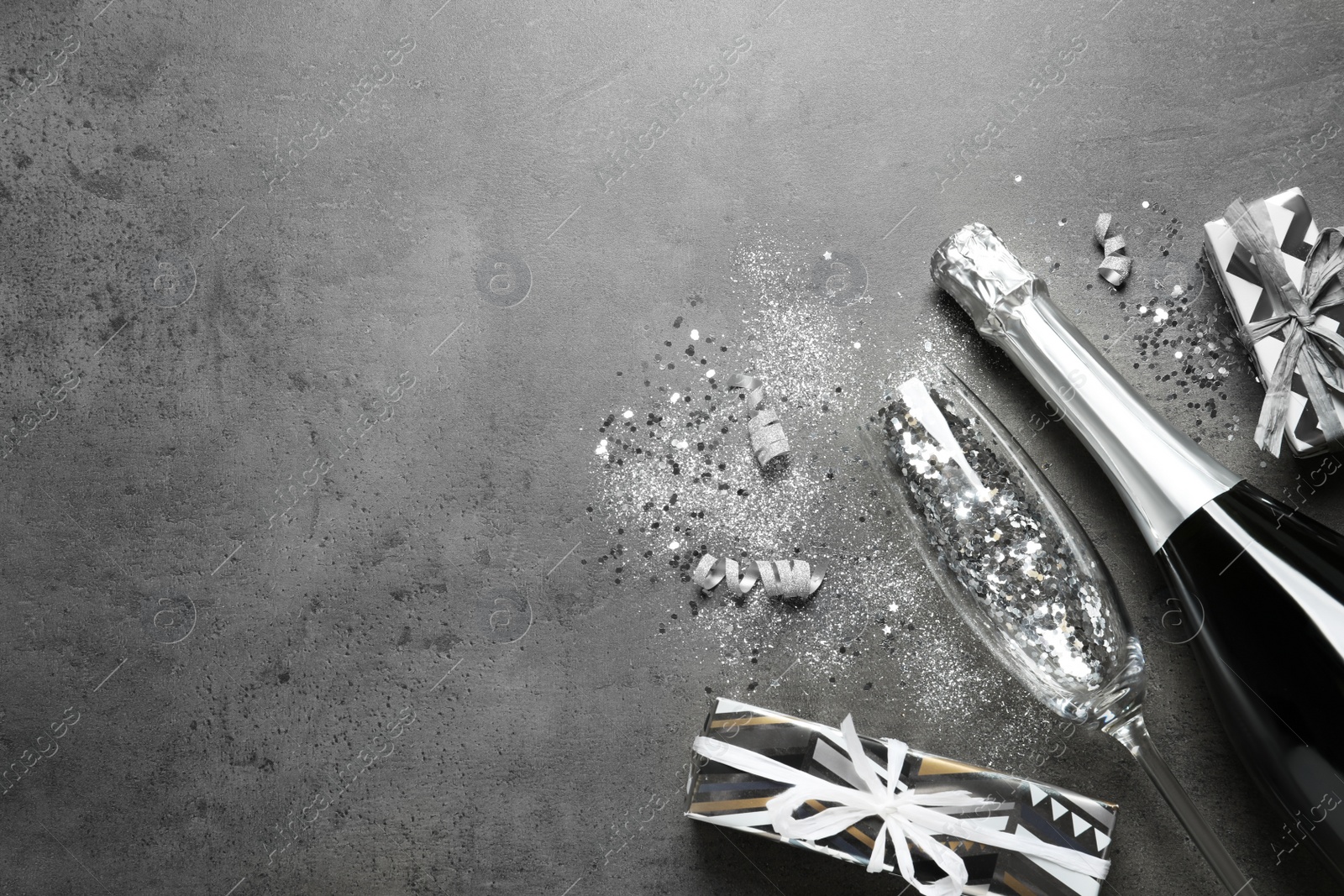 Photo of Flat lay composition with bottle of champagne for celebration on grey stone background. Space for text