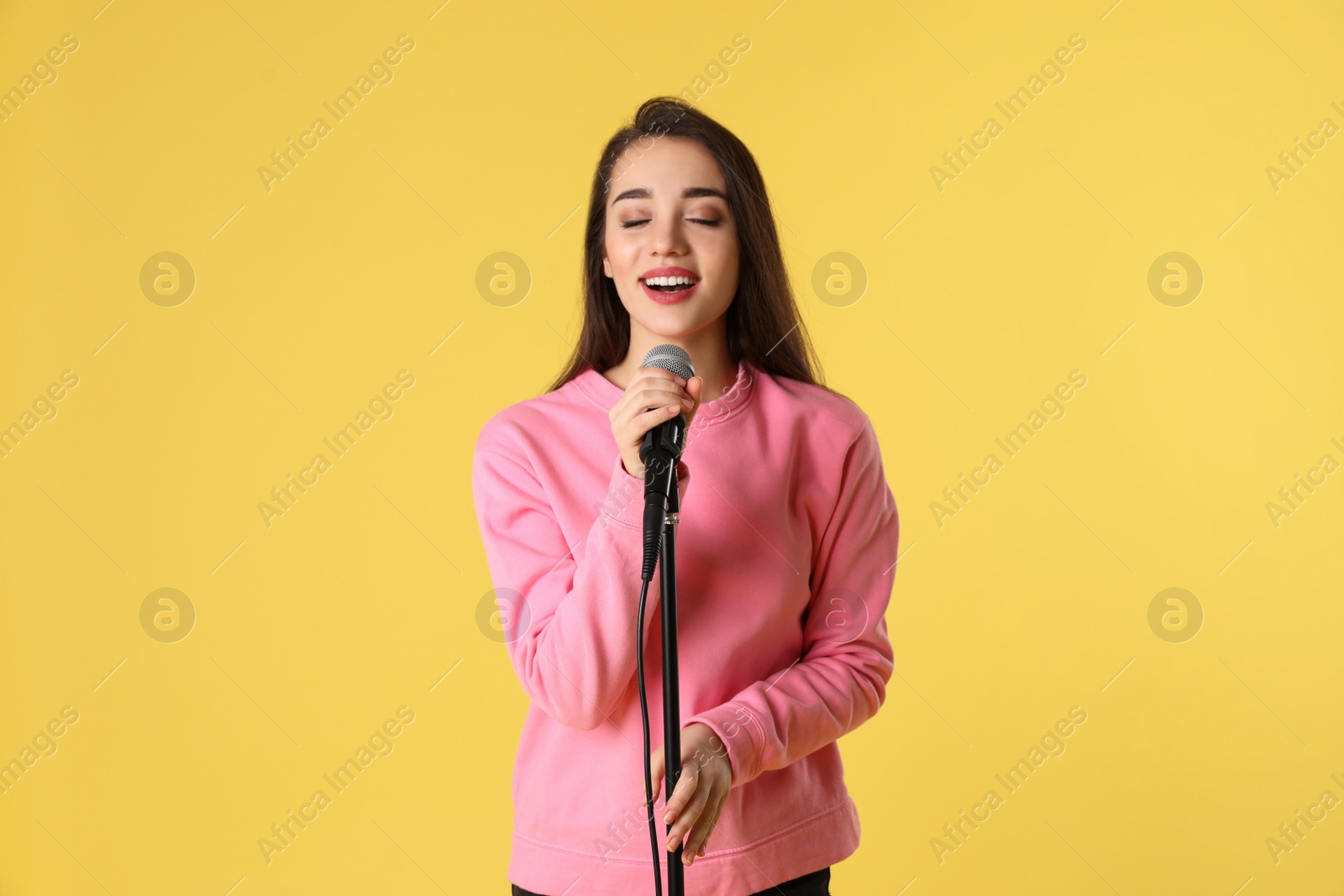 Photo of Young woman wearing casual clothes singing in microphone on color background