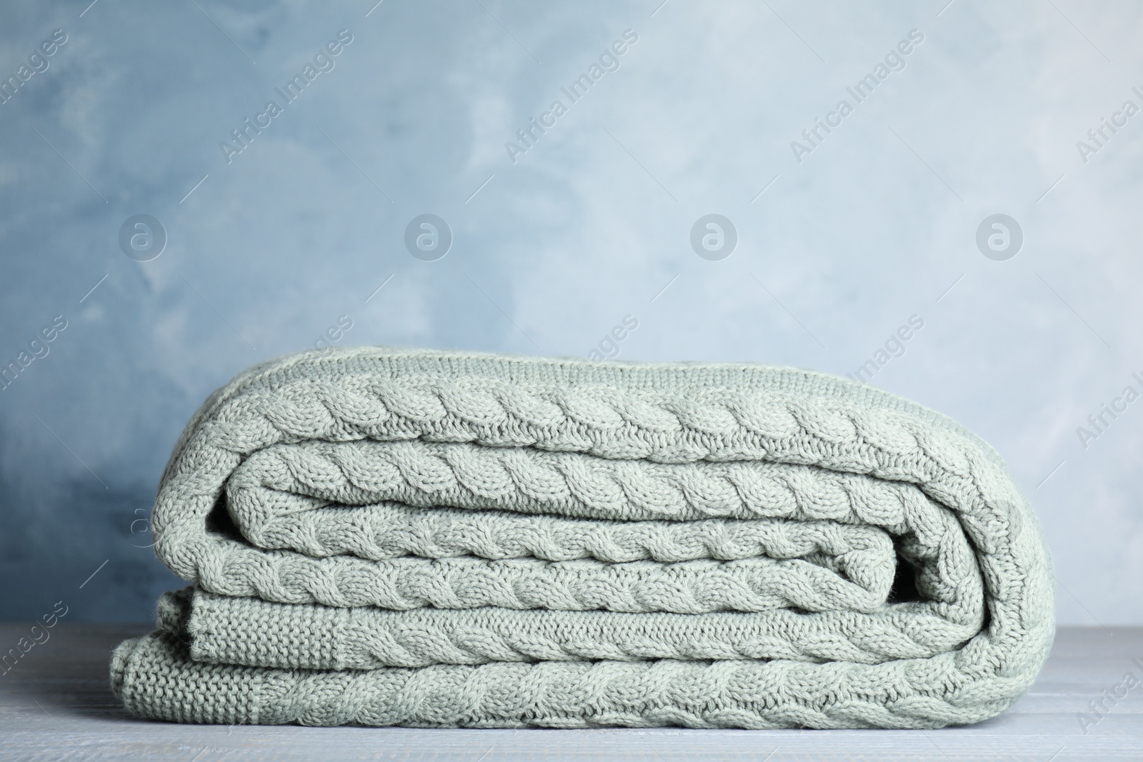 Photo of Knitted plaid on light grey wooden table