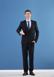 Photo of Business trainer reaching out for handshake on color wall background