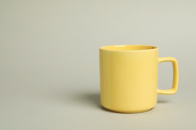 Photo of One yellow ceramic mug on light grey background, space for text