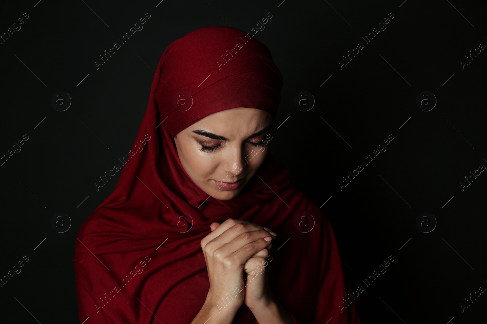 Photo of Portrait of Muslim woman in hijab  praying on dark background