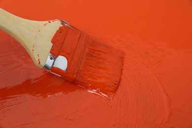 Applying orange paint with brush, closeup view