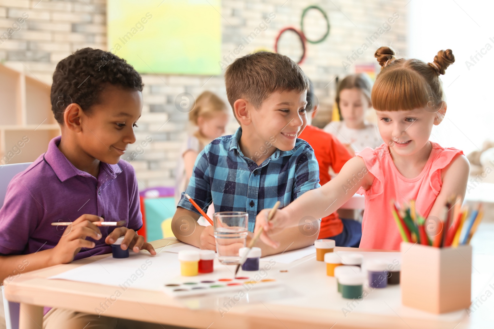 Photo of Cute little children painting at table indoors. Learning by playing