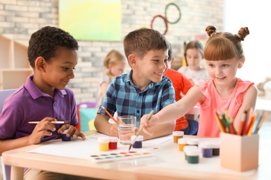 Photo of Cute little children painting at table indoors. Learning by playing