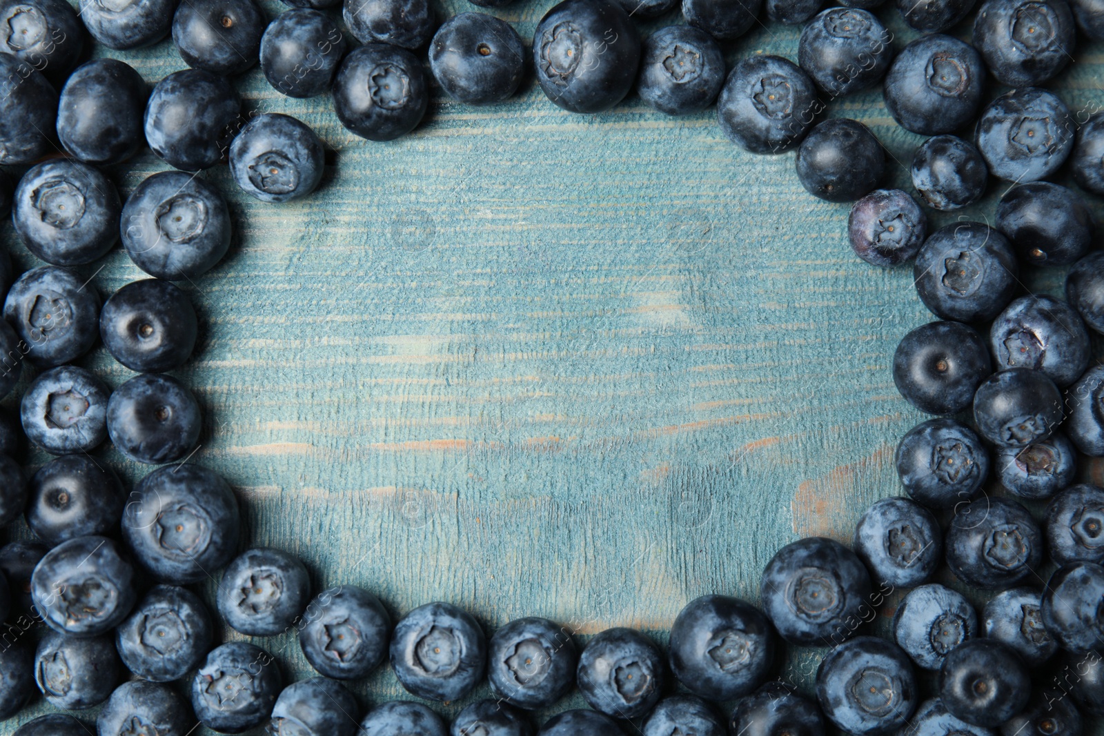 Photo of Frame made with fresh blueberries on wooden table, top view. Space for text