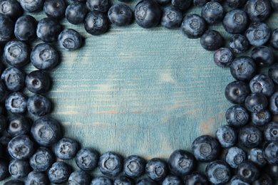 Photo of Frame made with fresh blueberries on wooden table, top view. Space for text