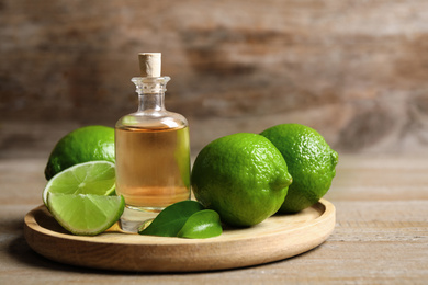 Photo of Lime essential oil and citrus fruits on wooden table