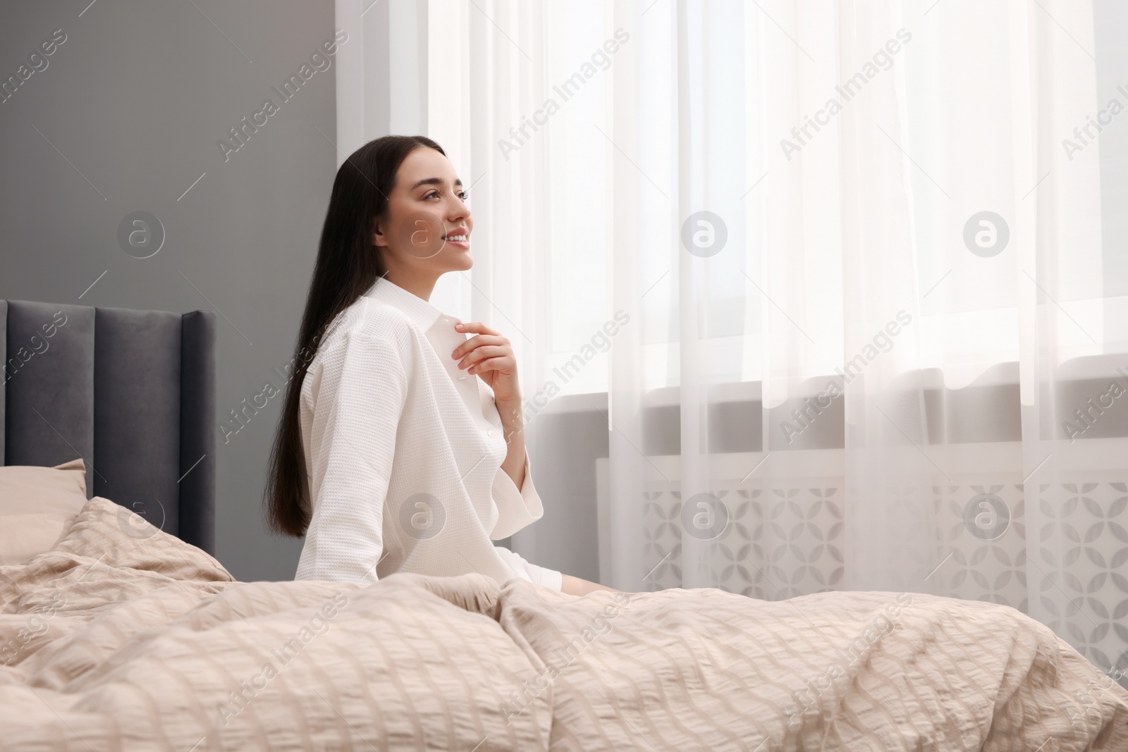 Photo of Beautiful woman sitting on bed at home, space for text. Lazy morning