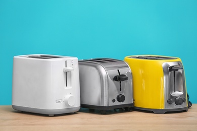 Photo of Different toasters on table against color background. Interior element