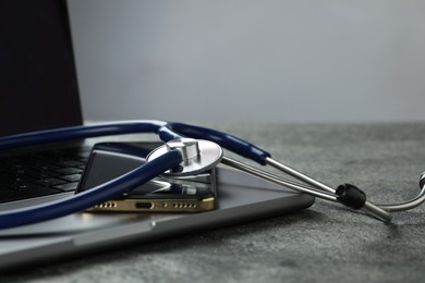 Photo of Modern electronic devices and stethoscope on grey table. Space for text