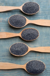 Poppy seeds in spoons on blue wooden table, flat lay