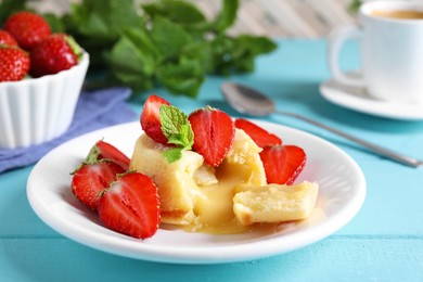 Tasty vanilla fondant with white chocolate and strawberries on light blue wooden table, closeup