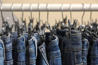 Photo of Rack with stylish jeans on color background, closeup
