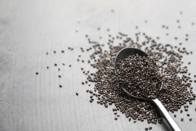 Spoon with chia seeds on grey table, space for text