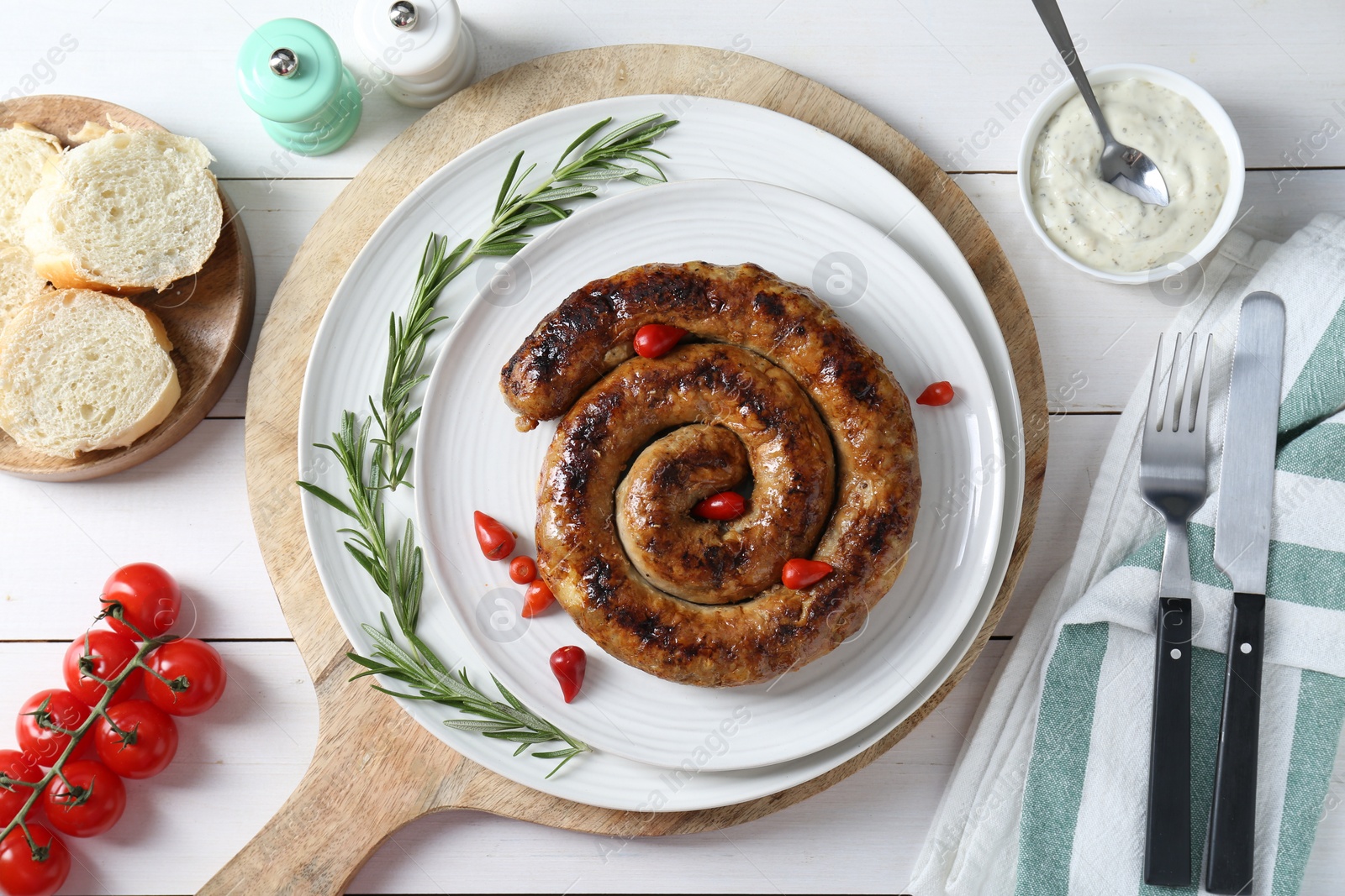 Photo of Tasty homemade sausages served on white wooden table, flat lay