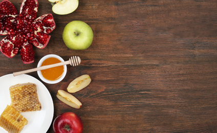 Photo of Flat lay composition with honey and fruits on wooden table, space for text. Rosh Hashanah holiday