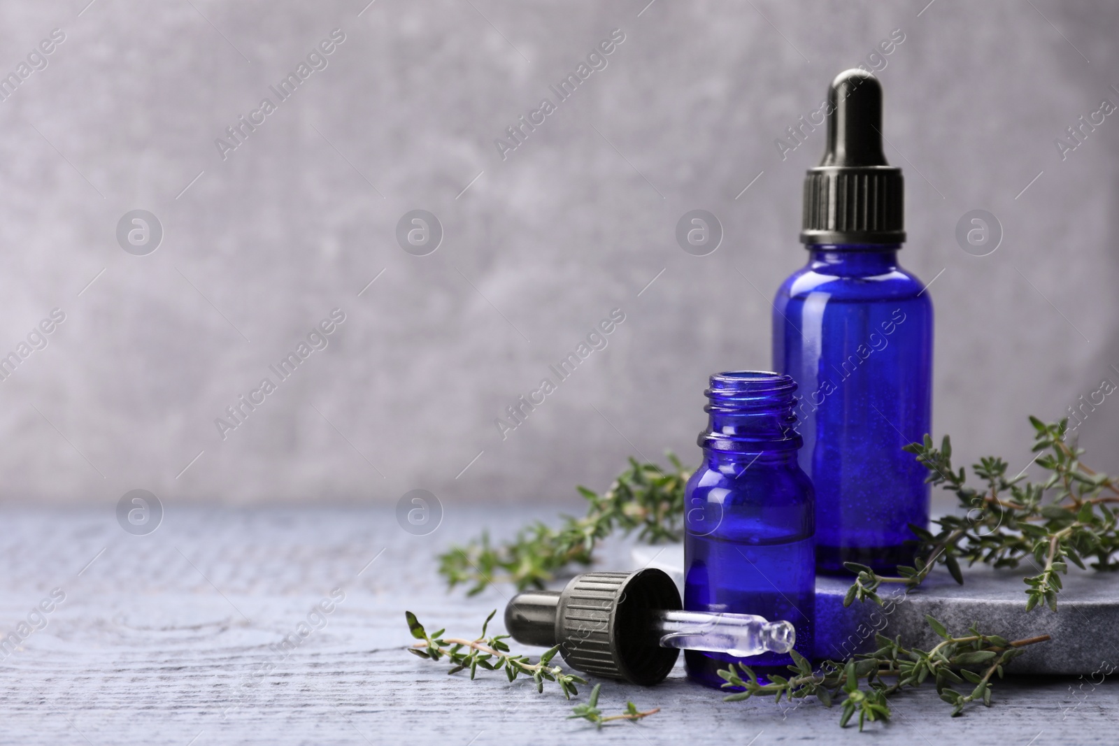 Photo of Thyme essential oil on light blue wooden table, space for text