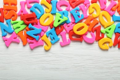 Photo of Colorful magnetic letters on white wooden table, flat lay. Space for text