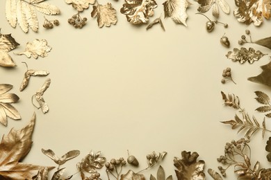Photo of Frame made of different golden leaves on beige background, flat lay with space for text. Autumn decor