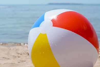 Photo of Wet colorful beach ball at seaside on sunny day, closeup