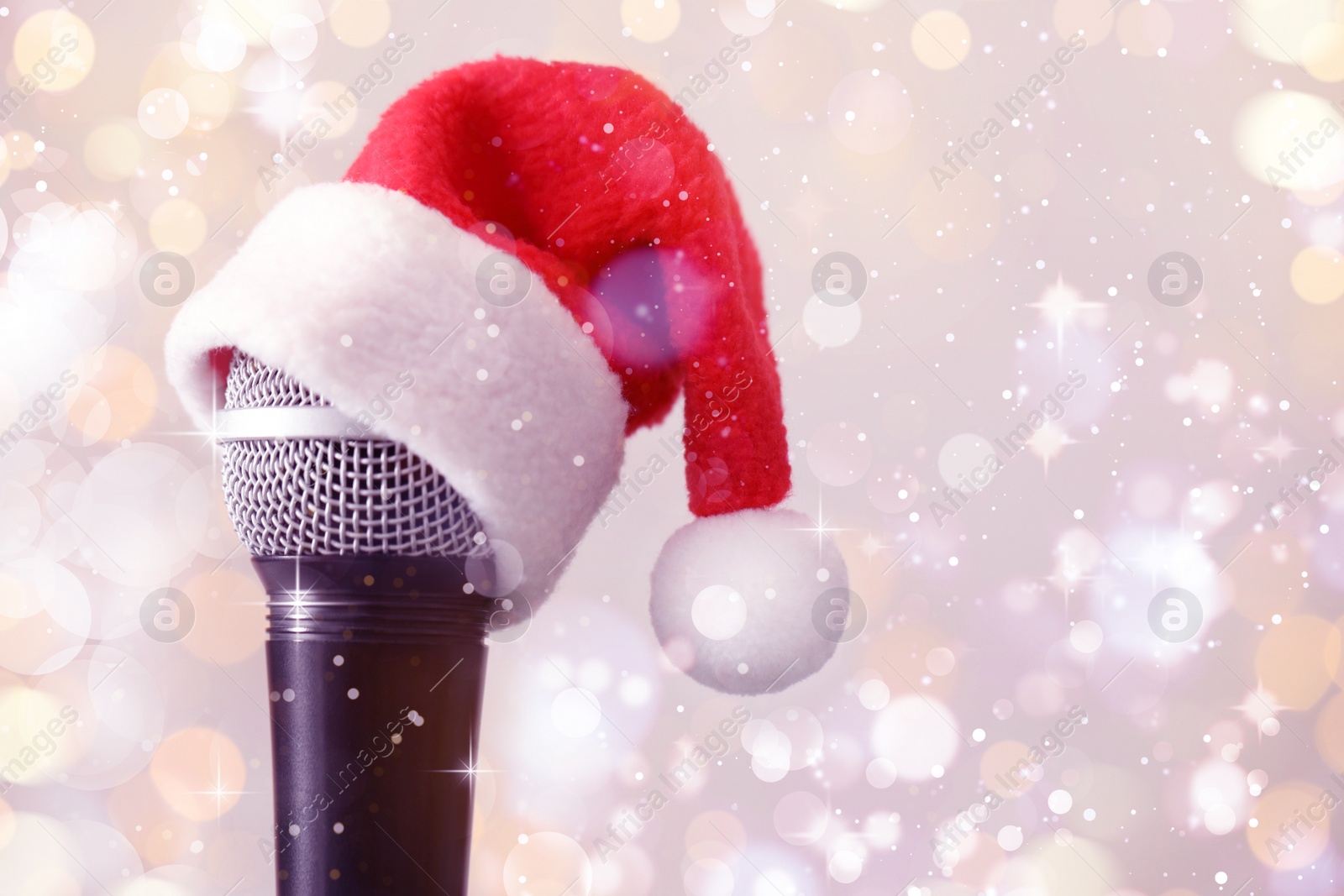 Image of Microphone with Santa hat against blurred lights, space for text. Christmas music
