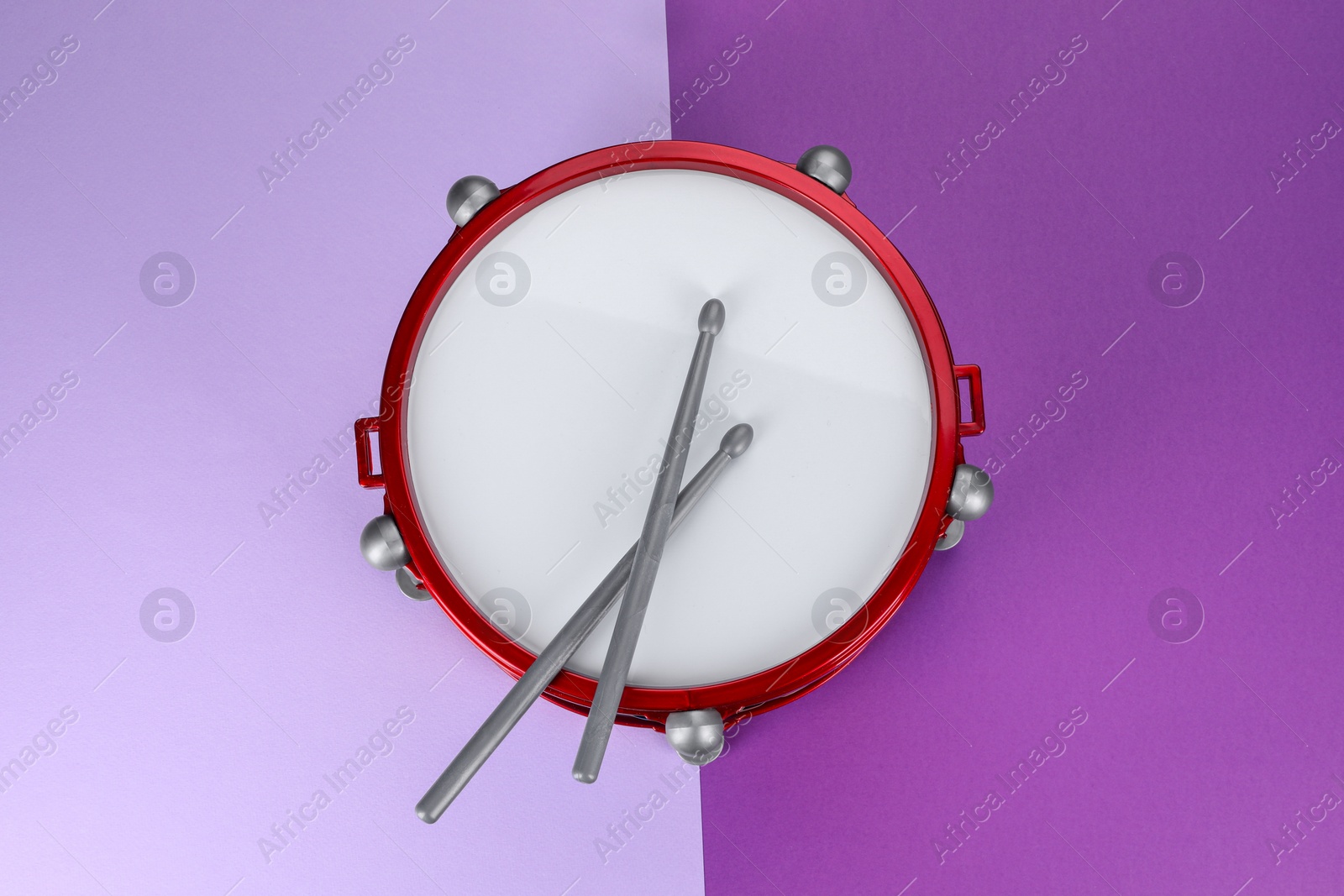 Photo of Children's drum with drumsticks on color background, top view