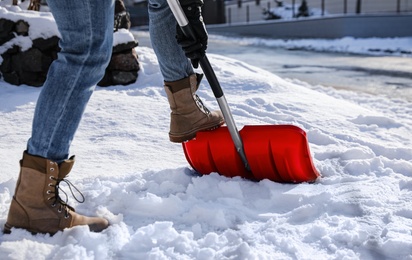 Person shoveling snow outdoors on winter day, closeup