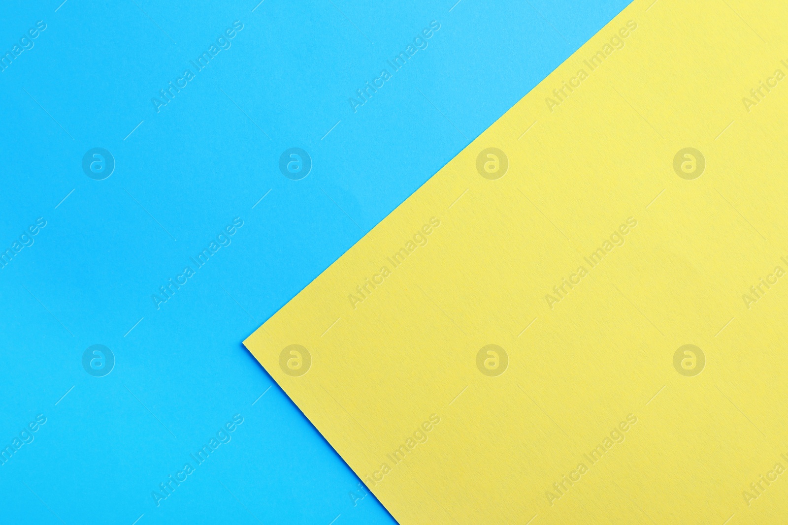 Photo of Blue and yellow paper sheets as colorful background, top view