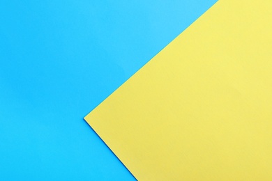 Photo of Blue and yellow paper sheets as colorful background, top view