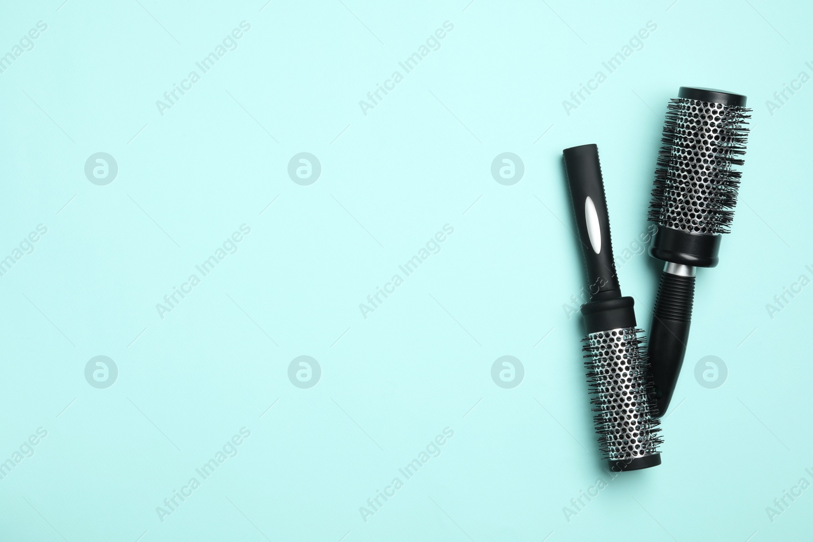 Photo of Modern round hair brushes on light blue background, flat lay. Space for text