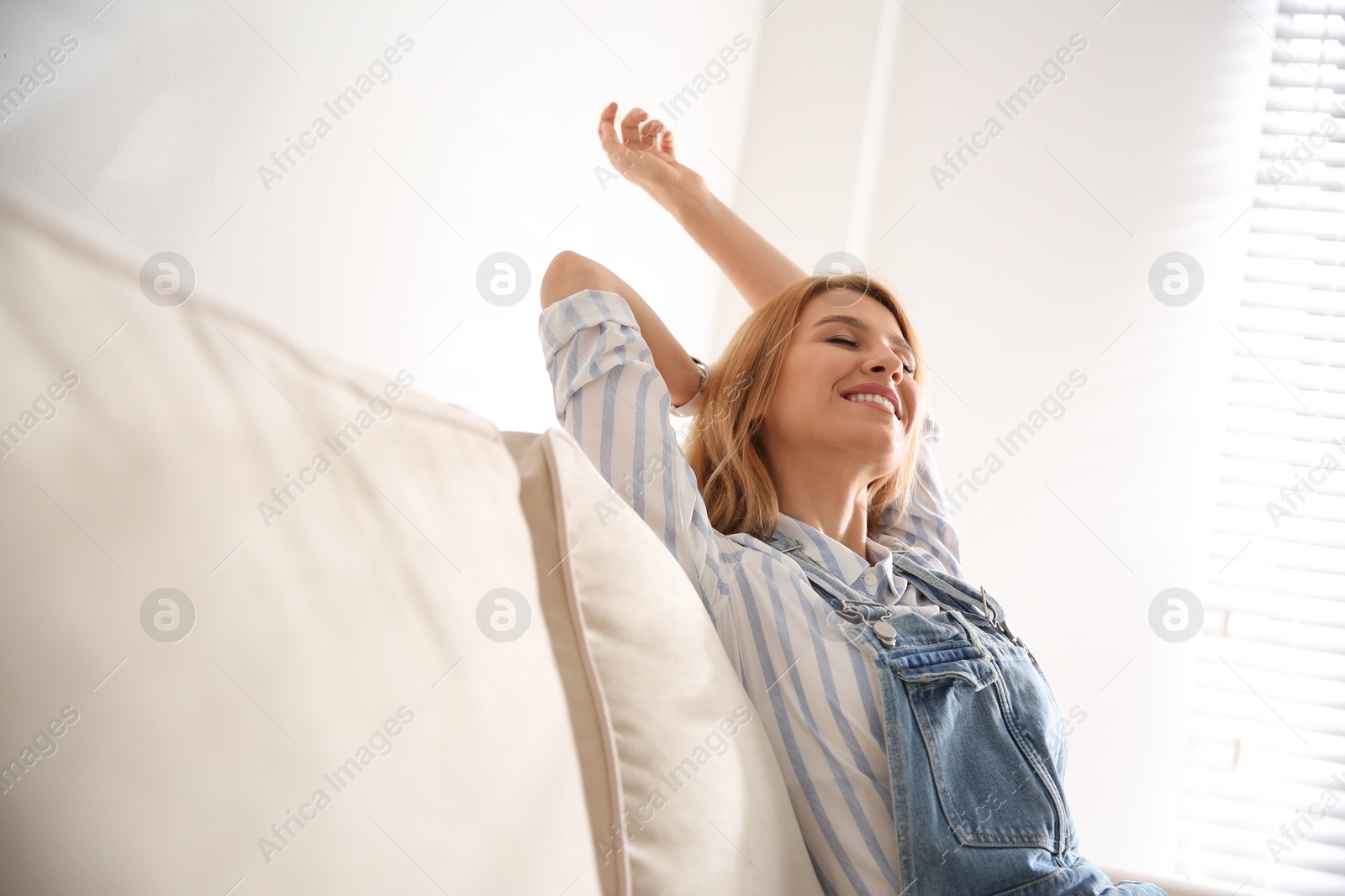 Photo of Young woman relaxing on couch near window at home