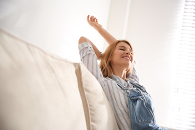 Photo of Young woman relaxing on couch near window at home