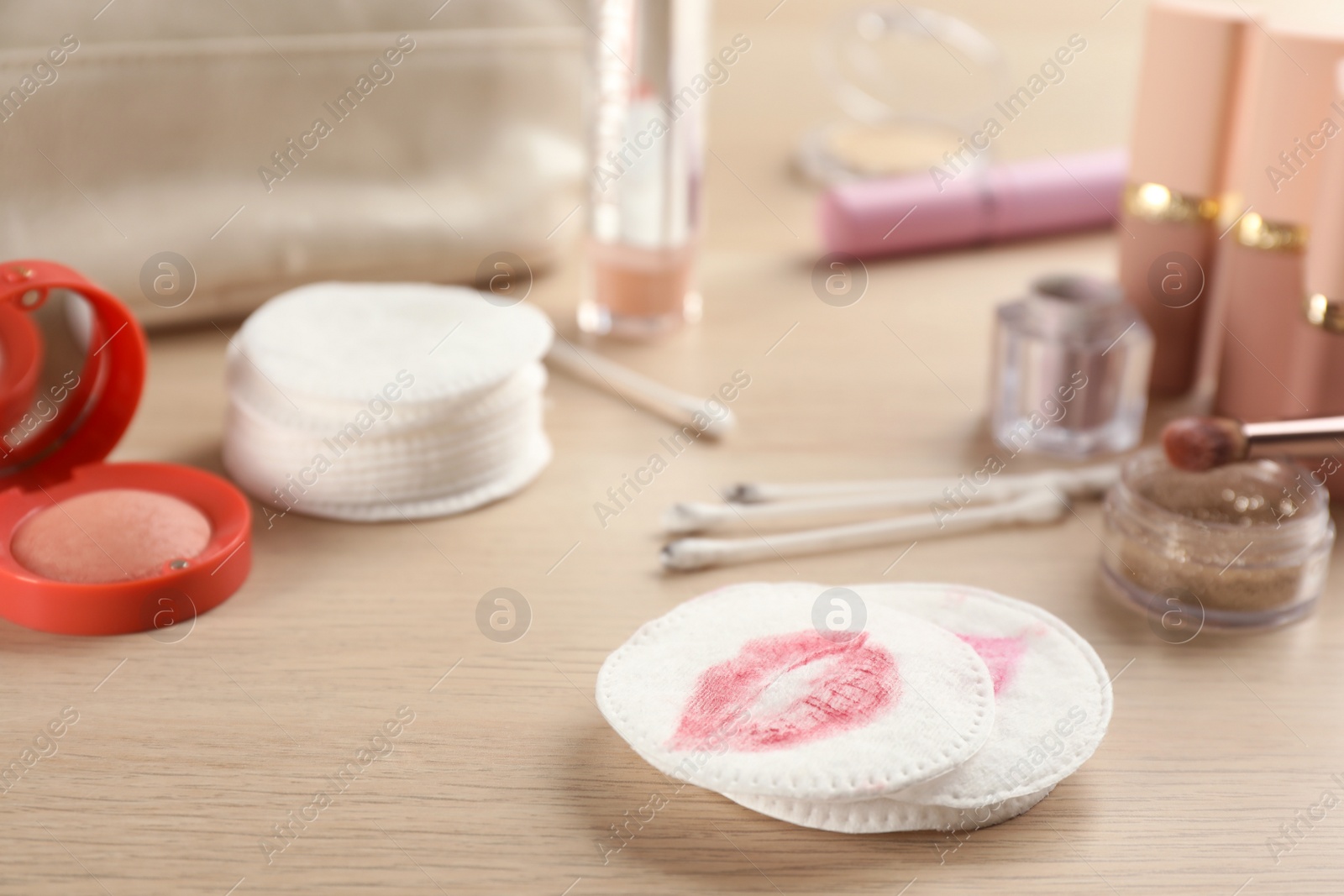 Photo of Dirty cotton pads, swabs and cosmetic products on wooden table