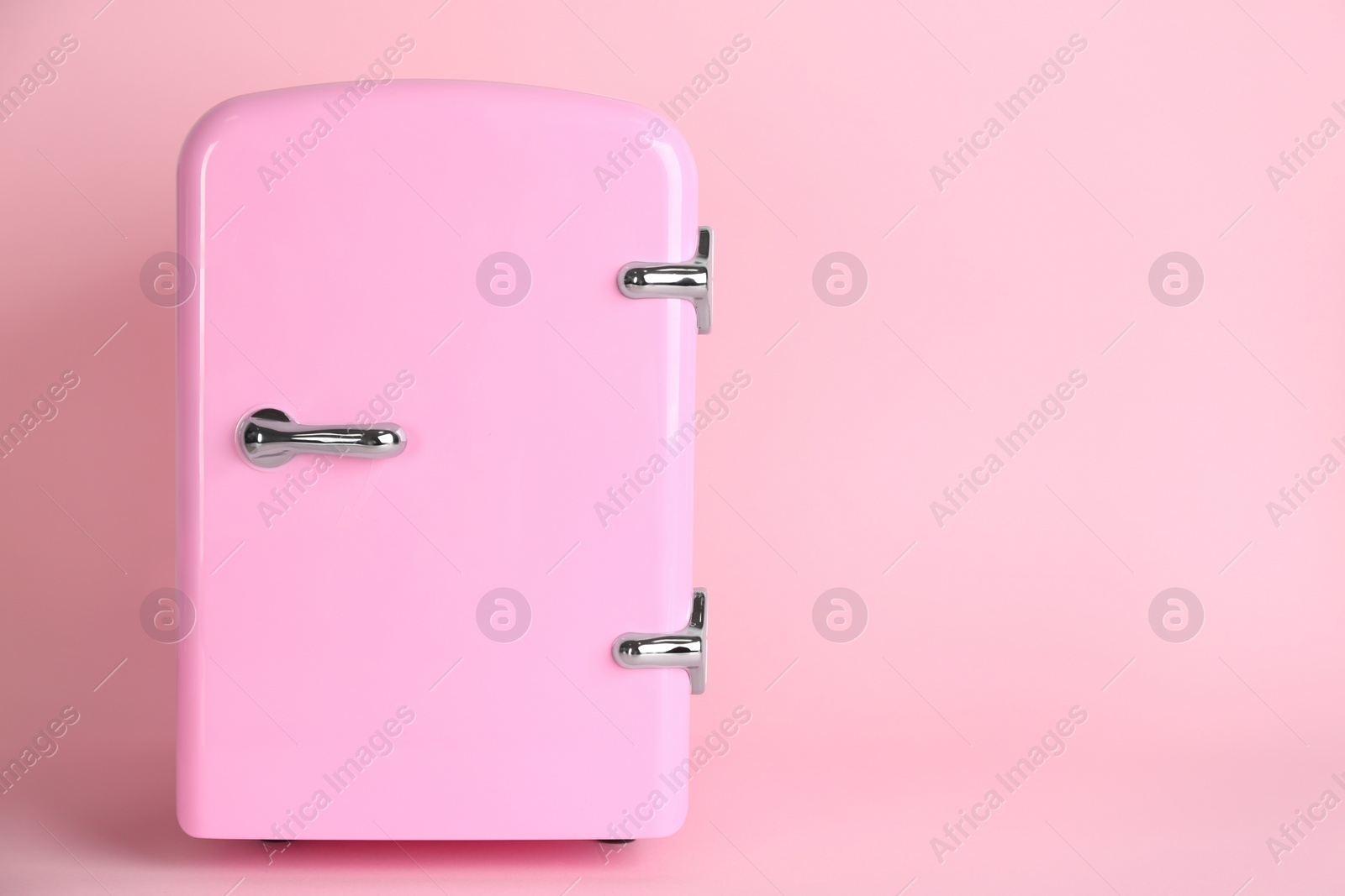 Photo of Cosmetic refrigerator on pink background, space for text